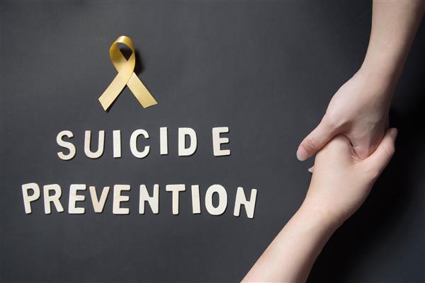 Gold ribbon with the words "Suicide Prevention" below and two hands pulling each other up